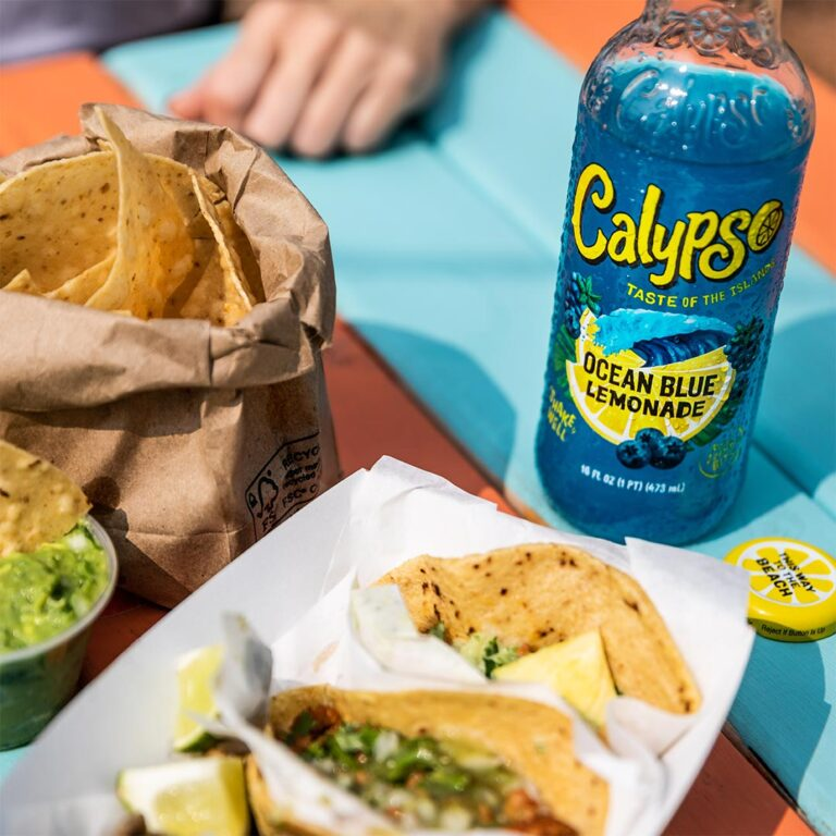 Calypso Ocean Blue Lemonade 473ml bottle with snacks outdoors.